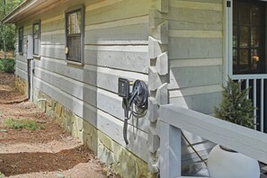 Ein rustikales Holzhaus mit weißer Fassade, einem kleinen Fenster und einer Steckdose an der Seite.