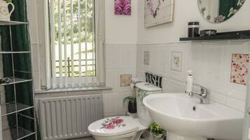 A bathroom with a toilet, sink, and window with blinds.