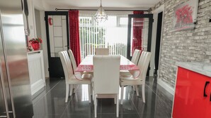 Un comedor con una mesa y sillas blancas, un armario rojo y una cocina con refrigerador.