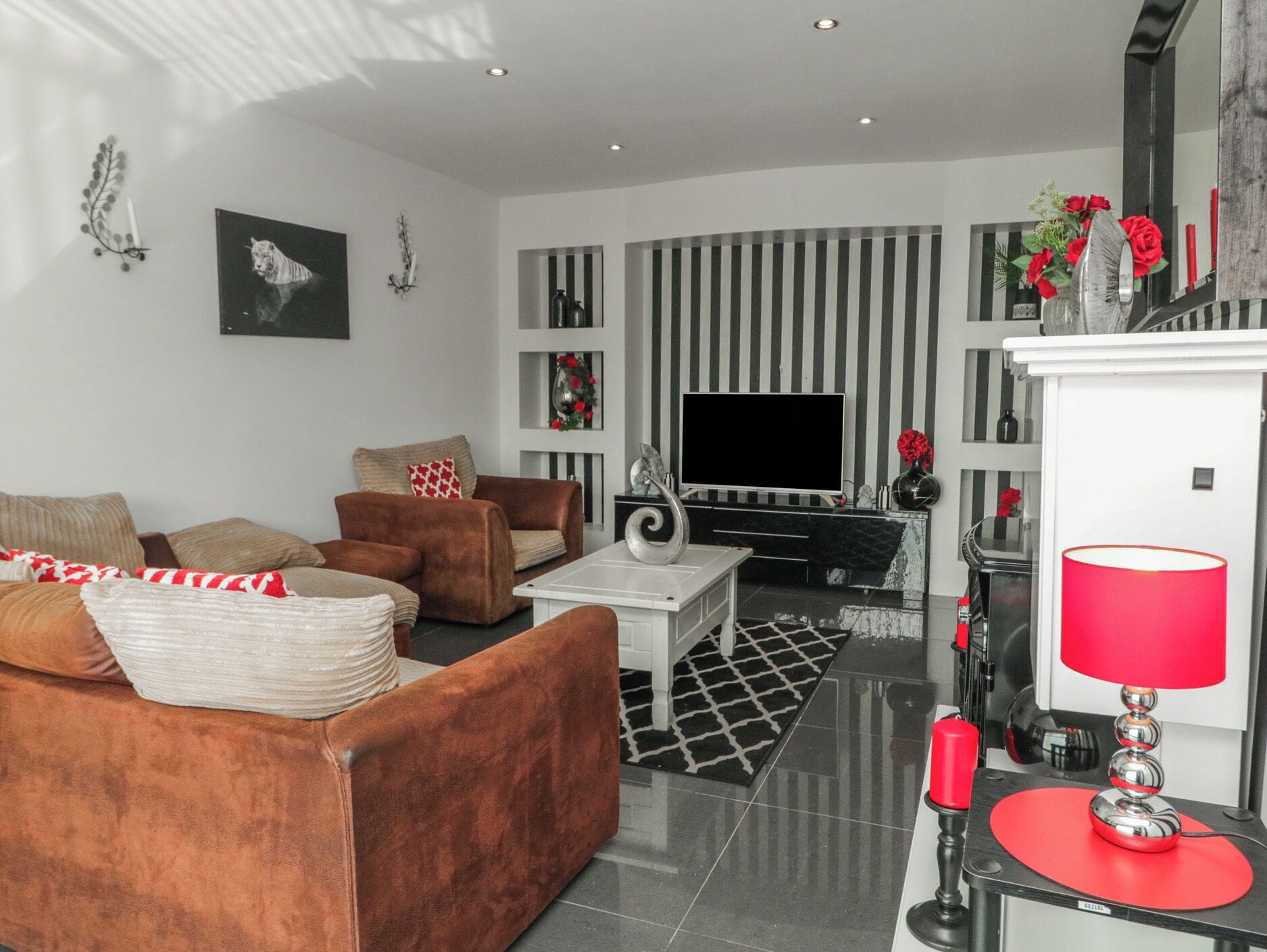 Un salon moderne comprenant un canapé, des fauteuils, une table basse, un téléviseur à écran plat et des objets de décoration.