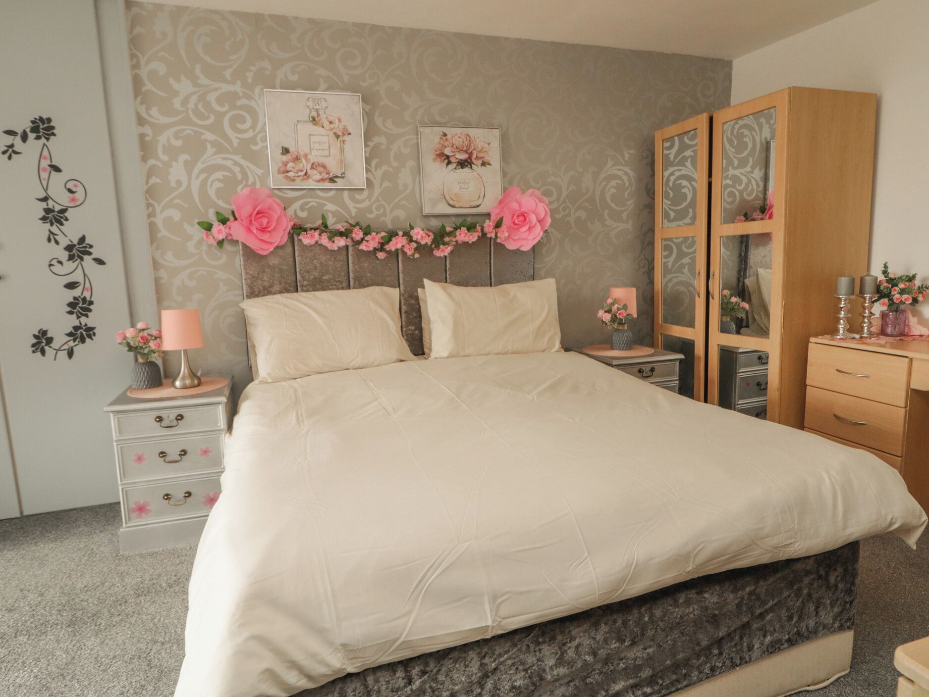 A bedroom with a large bed, a dresser, a nightstand, and a cabinet.