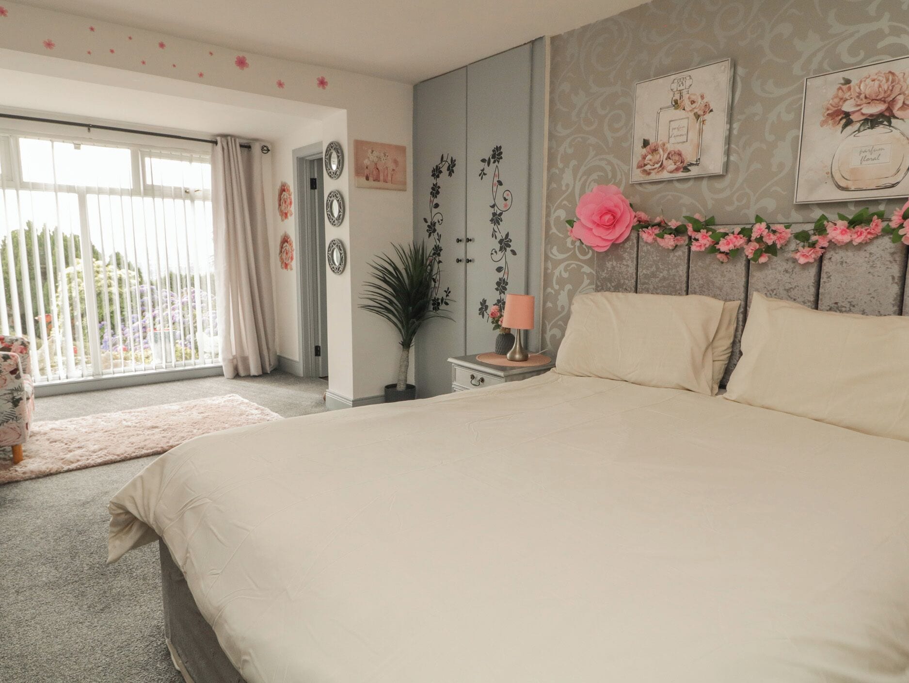 A bedroom with a large bed, a nightstand, a lamp, and a window with curtains.