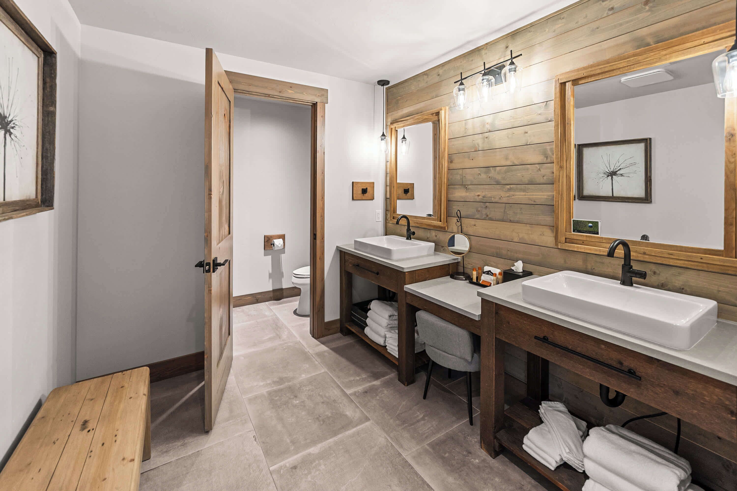 A modern bathroom with wooden paneling, two sinks, and a large mirror.