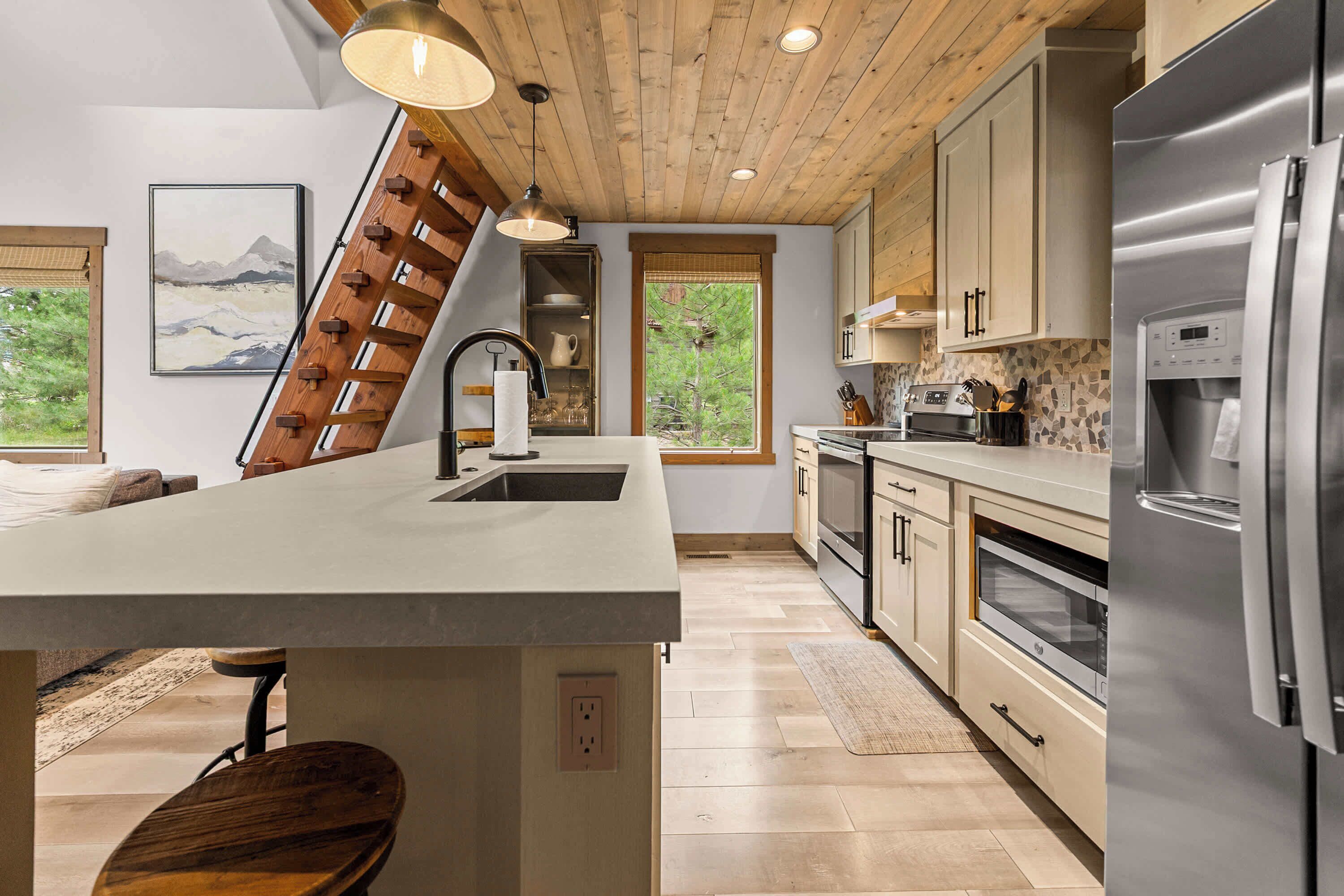 Una cocina moderna con una isla central, electrodomésticos de acero inoxidable y techo de madera.