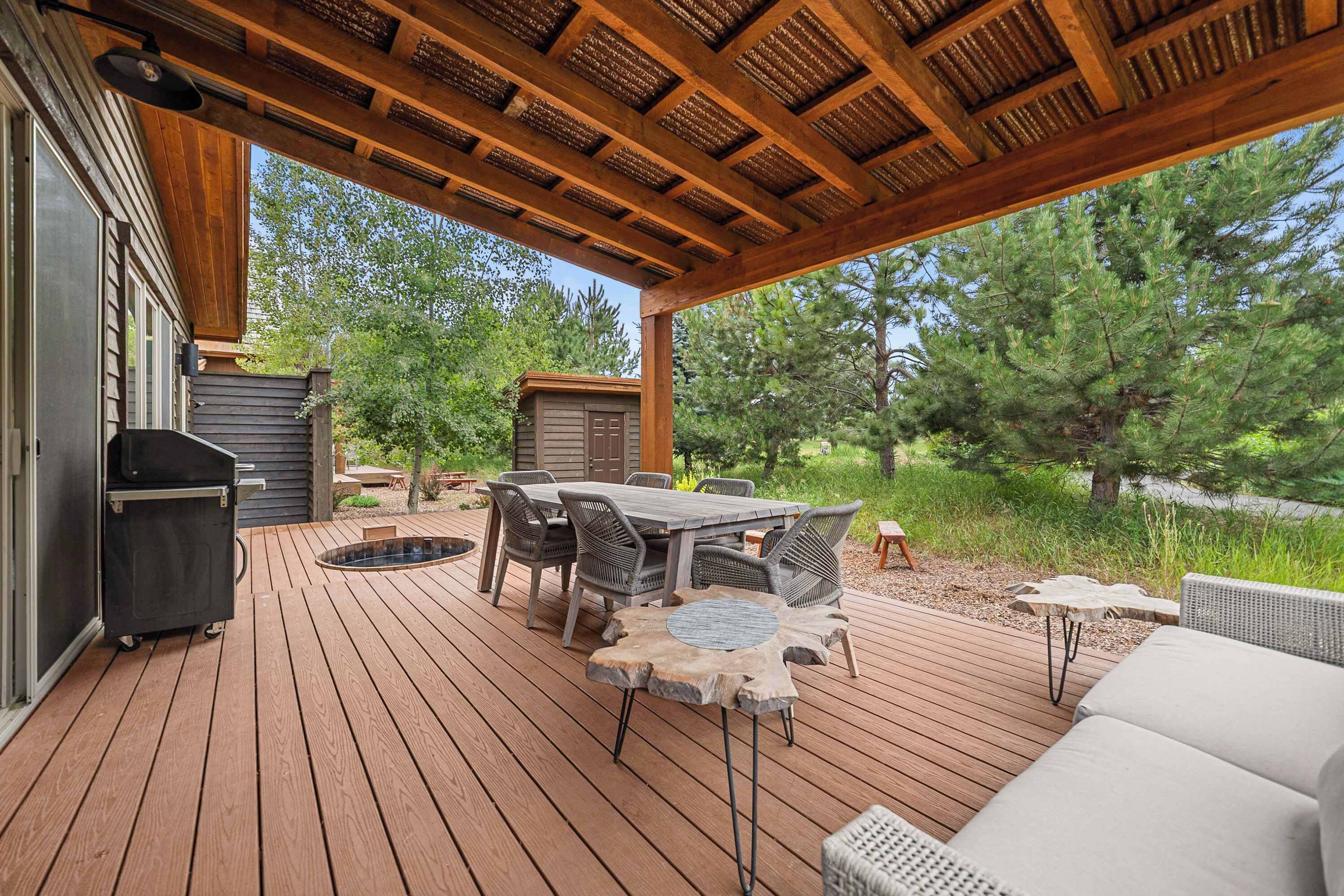 An outdoor deck with a wooden table and chairs, a barbecue grill, and a hot tub.