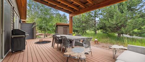 An outdoor deck with a wooden table and chairs, a barbecue grill, and a hot tub.