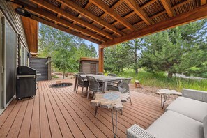 An outdoor deck with a wooden table and chairs, a barbecue grill, and a hot tub. - Wilderness Club Park Cottage (Eureka)