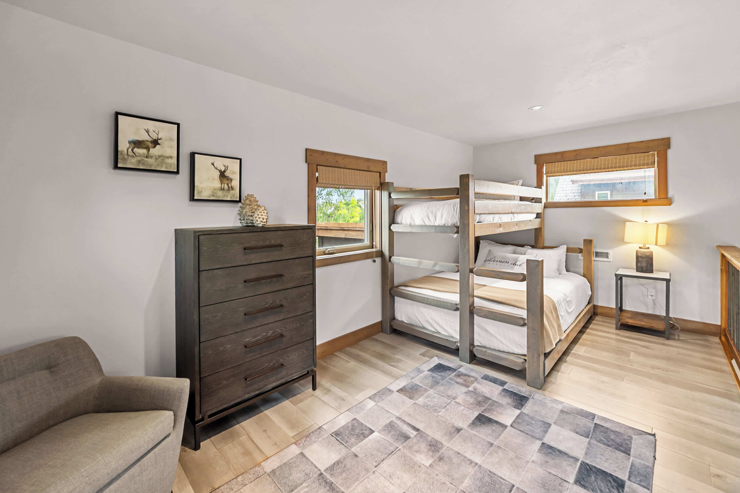 A bedroom with a bunk bed, a dresser, a chair, and a window with a view.