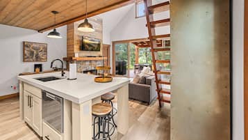 A spacious kitchen with a large island, wooden ceiling, and a view of the outdoors.