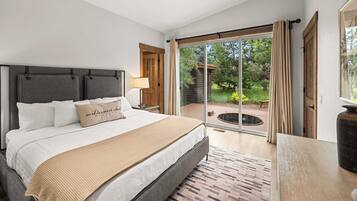 A bedroom with a bed, a nightstand, a lamp, and a view of a garden through a sliding glass door.