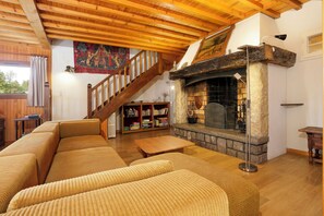 Ein gemütliches Wohnzimmer mit Holzboden, Kamin, Treppe und Bücherregal.