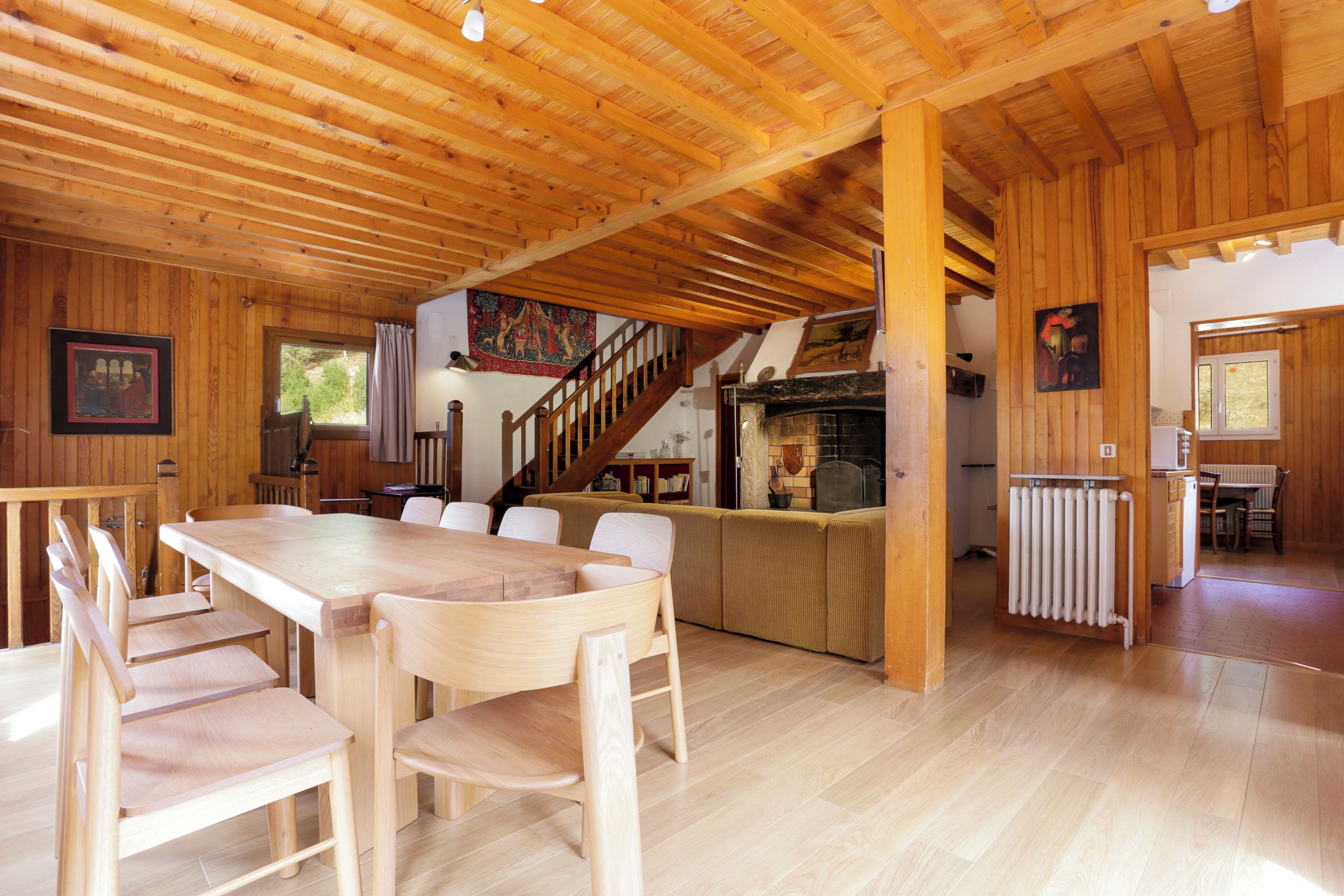 A wooden interior with a dining area, kitchen, and a staircase.