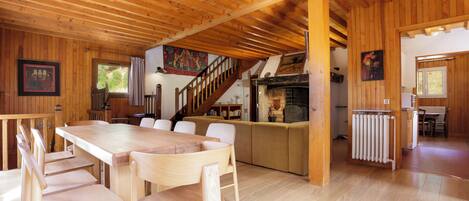 A wooden interior with a dining area, kitchen, and a staircase.