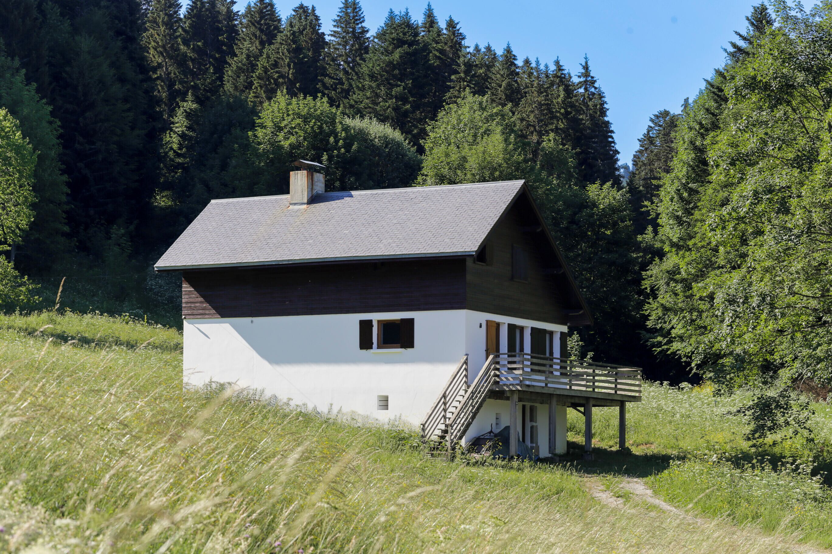 Ein eingeschossiges Haus mit geneigtem Dach, einer kleinen Veranda und einer Treppe zum Eingang.