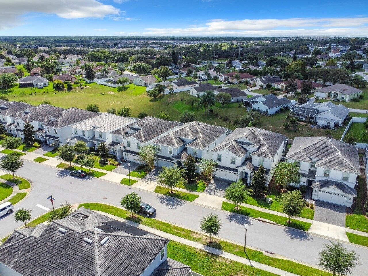 Un quartier résidentiel composé de maisons individuelles, une rue principale et un ciel dégagé.