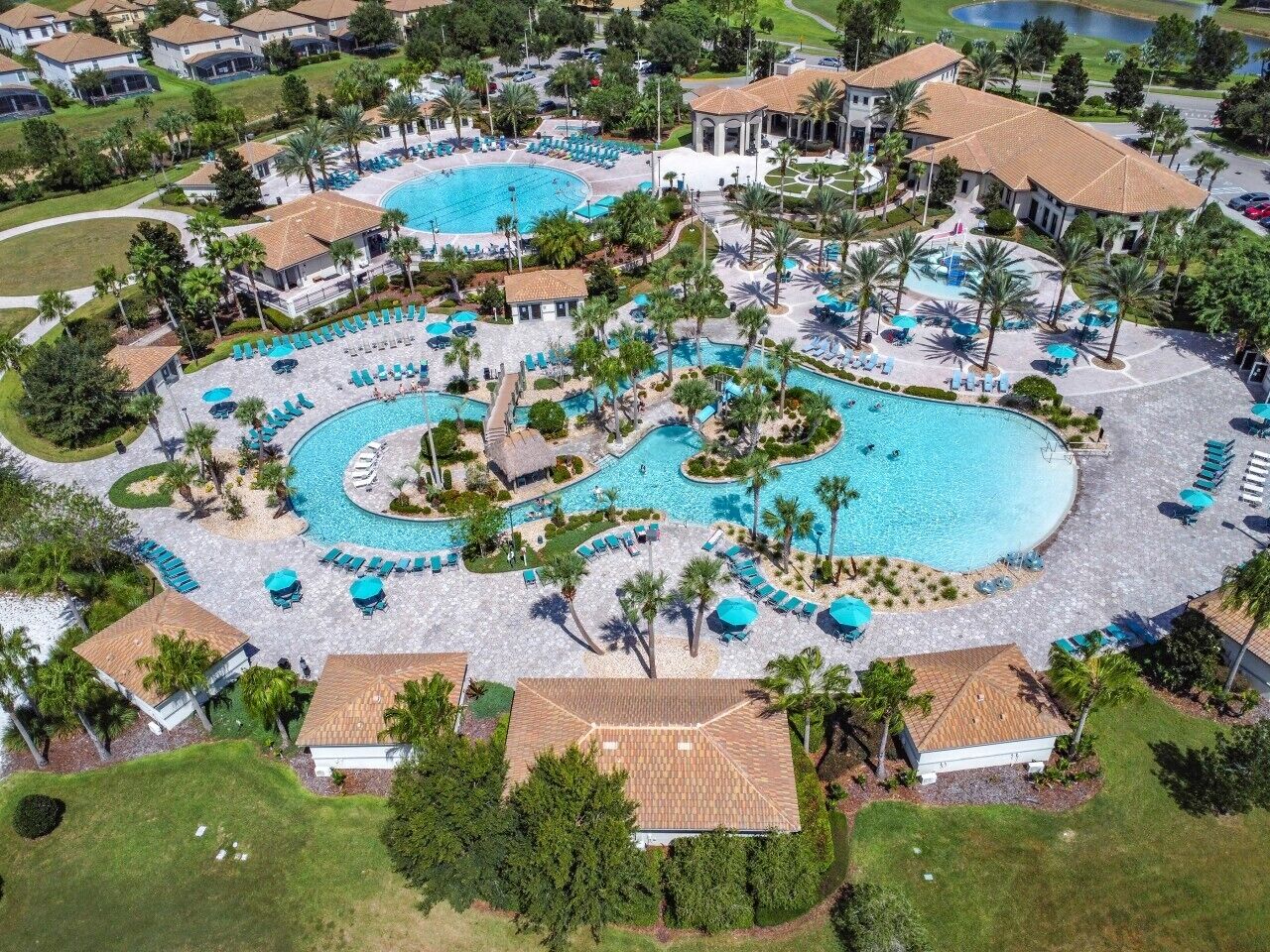 A resort with multiple swimming pools, sun loungers, and palm trees.