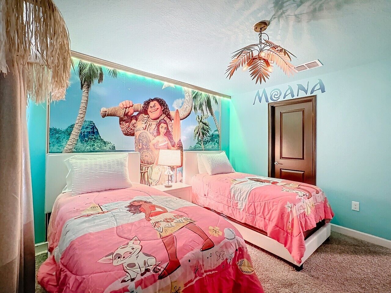 Un dormitorio con dos camas, un mural, una puerta y un ventilador de techo.