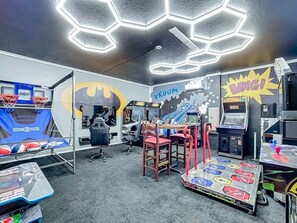 A gaming arcade with various machines, a basketball hoop, and a table with game tokens. - Luxury 8BR ChampionsGate Villa w/ Pool & Theater (Davenport)