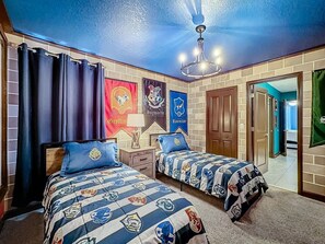 Une chambre avec deux lits, un lustre et un mur en briques orné de banderoles.