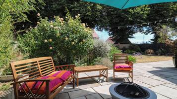 An outdoor patio with a fire pit, wooden furniture, and a large umbrella.