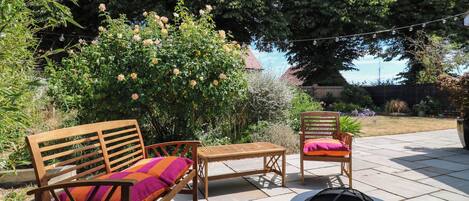 Un patio al aire libre con un brasero, muebles de madera y una sombrilla grande.
