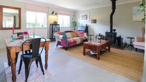 A cozy living room with a fireplace, a dining area with a table and chairs, and a comfortable sofa. - The Annexe @ Shotley Cottage (Ipswich)
