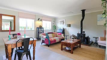 A cozy living room with a fireplace, a dining area with a table and chairs, and a comfortable sofa.