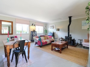 A cozy living room with a fireplace, a dining area with a table and chairs, and a comfortable sofa. - The Annexe @ Shotley Cottage (Ipswich)