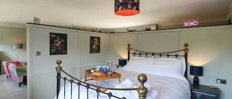 A bedroom with a four-poster bed, bedside tables, a nightstand, and a hanging lamp.
