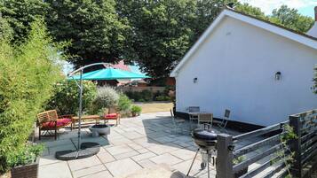 Un patio al aire libre con una parrilla, asientos y una sombrilla.