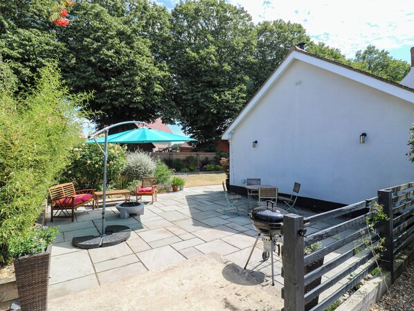An outdoor patio area with a barbecue grill, seating arrangements, and a covered umbrella. - The Annexe @ Shotley Cottage (Ipswich)