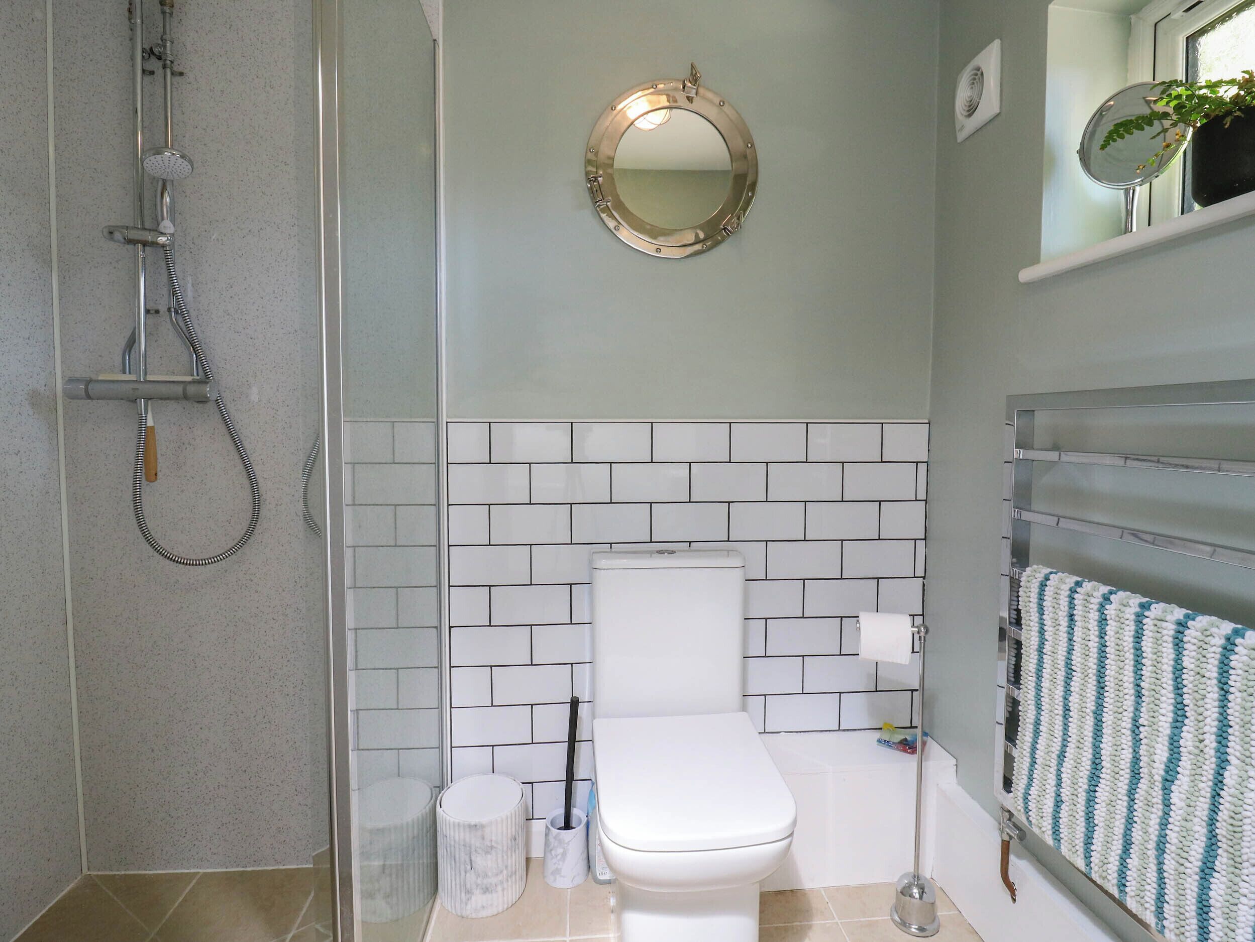 A bathroom with a shower, toilet, and a mirror.