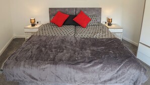 Una cama con cabecera estampada, dos mesitas de noche con lámparas y un cuadro en la pared.