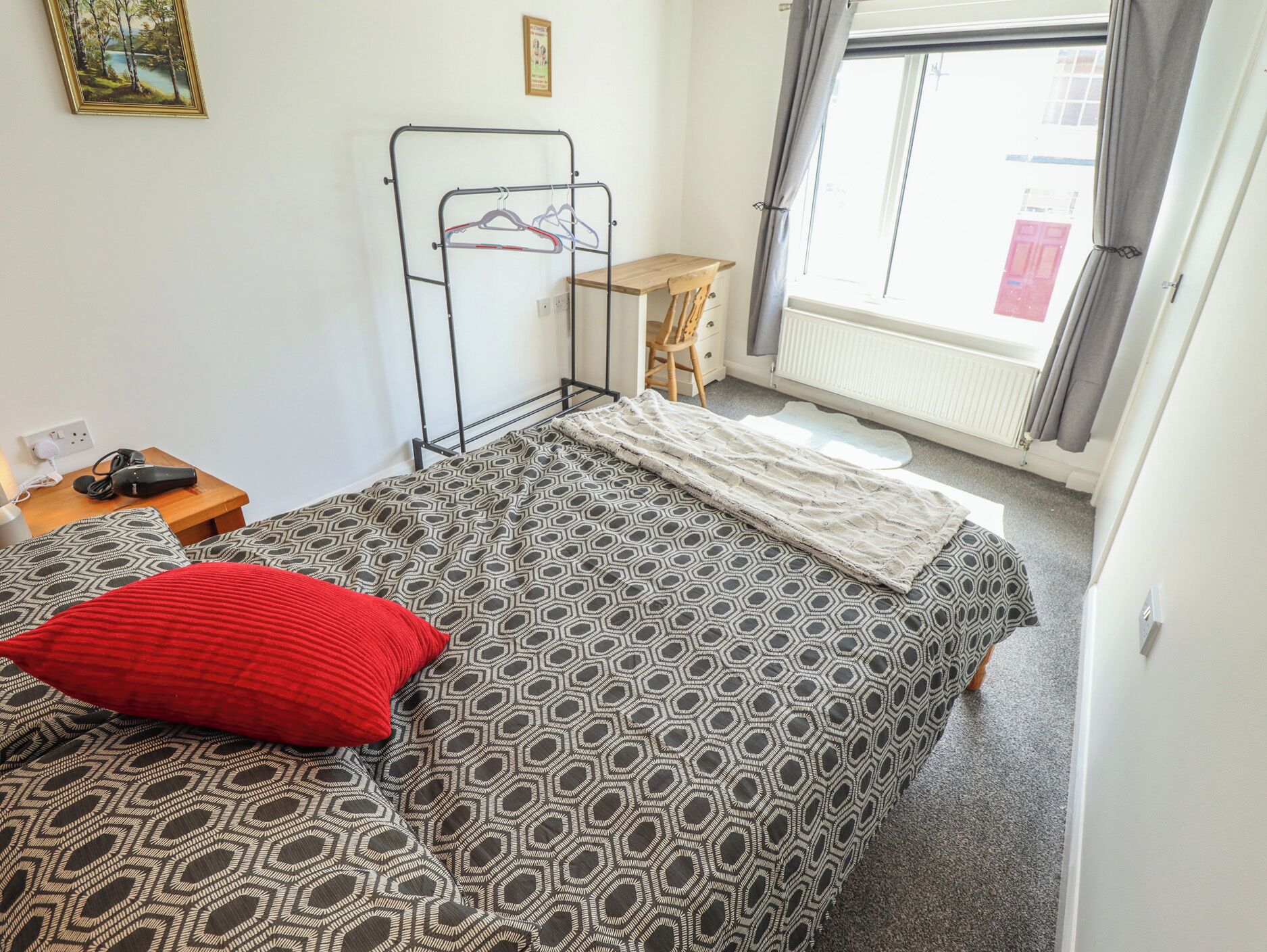 Une chambre à coucher avec un lit, un bureau, une chaise et un radiateur.