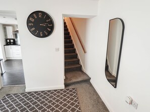 Una escalera con barandilla, un reloj de pared negro y un espejo.