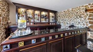 A bar area with a stone wall, wooden bar counter, and various bottles and glasses. - Domaine Marie-Louise: A Getaway in the Basque Country (Orègue)