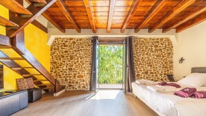 A room with a bed, a staircase, and a stone wall. - Domaine Marie-Louise: A Getaway in the Basque Country (Orègue)