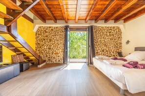 A room with a bed, a staircase, and a stone wall. - Domaine Marie-Louise: A Getaway in the Basque Country (Orègue)