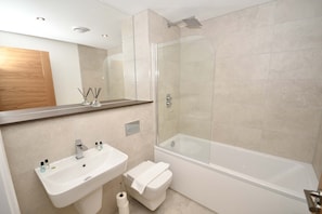 Uma casa de banho moderna com cabine de duche de vidro, lavatório branco e sanita.