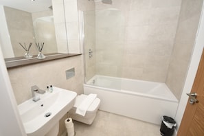 A modern bathroom with a white sink, mirror, and a glass-enclosed shower area. - Stylish 1 Bedroom Apartment in Central Leeds (Leeds)