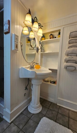 A bathroom with a pedestal sink, multiple mirrors, and a towel rack. - Hidden Treasure at Forsyth Park (Savannah)