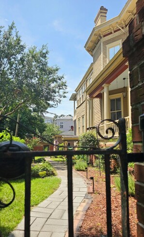 A pathway leading to a building with a traditional architectural style, including a prominent entrance with a porch and columns. - Hidden Treasure at Forsyth Park (Savannah)