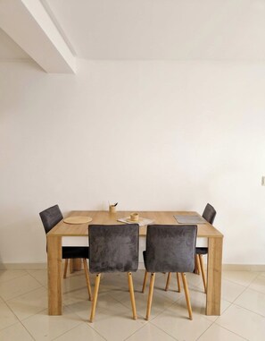 A dining area with a wooden table and four chairs, a woven placemat, and a small woven basket on the table. - Tangier Timber Loft Apartment (Spotify, IPTV) (Tanger)