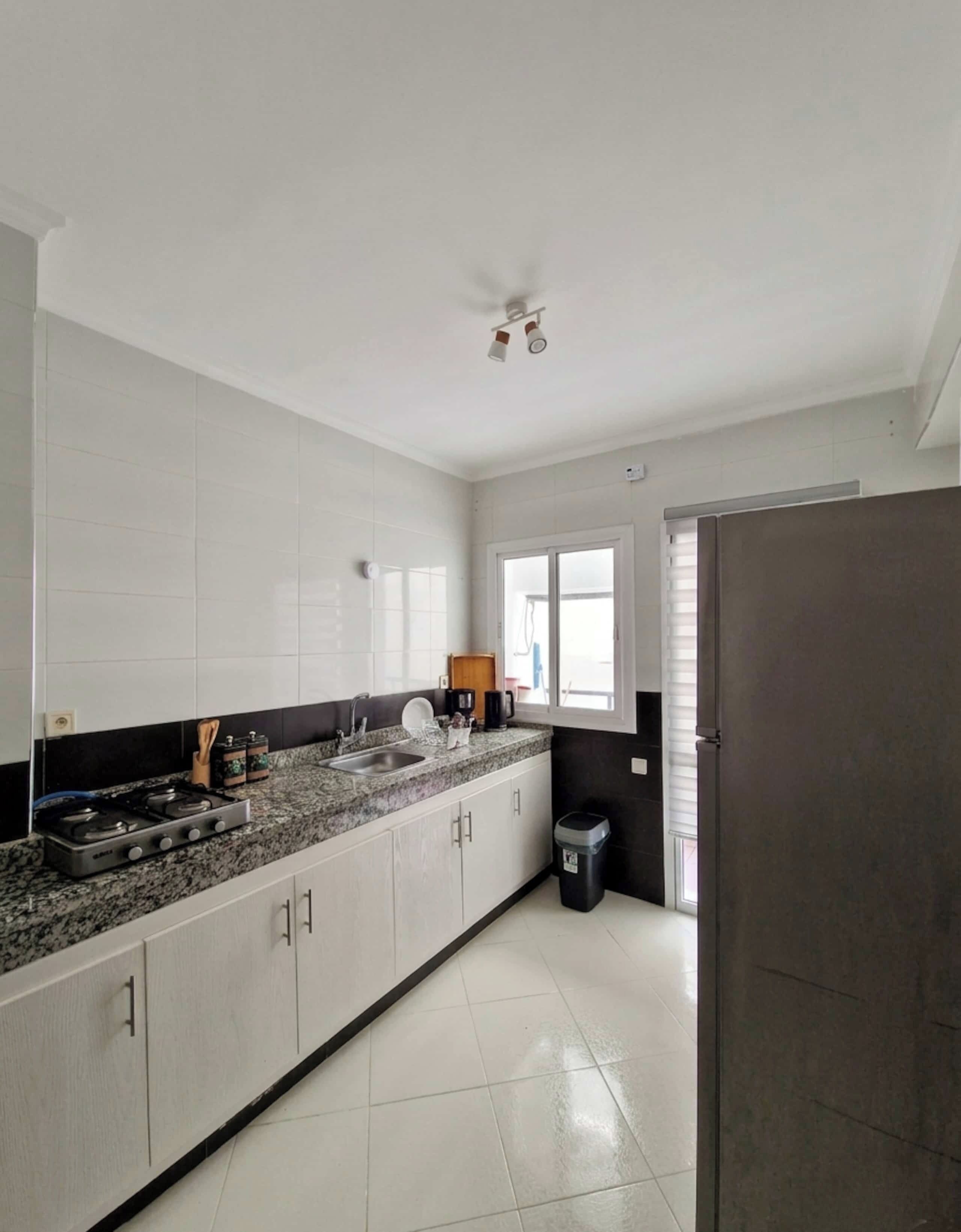 A kitchen with white cabinets, a granite countertop, a stove, and a window.