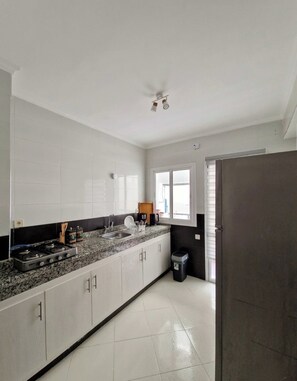 A kitchen with white cabinets, a granite countertop, a stove, and a window. - Tangier Timber Loft Apartment (Spotify, IPTV) (Tanger)