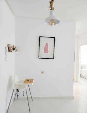 A minimalist room with a white wall, a framed picture, a white chair, and a small table. - Tangier Timber Loft Apartment (Spotify, IPTV) (Tanger)