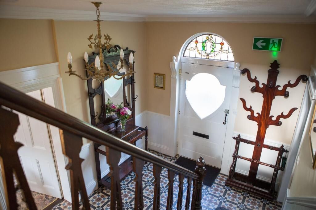 A staircase leading to a room with a white door, a chandelier, and a green exit sign.