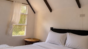 Ein Schlafzimmer mit einem Bett, einem Nachttisch, einem Fenster mit Vorhängen und einer Pendelleuchte.