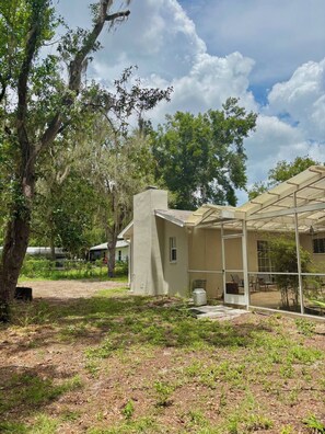 Una casa con un portico coperto, circondata da alberi e vegetazione.