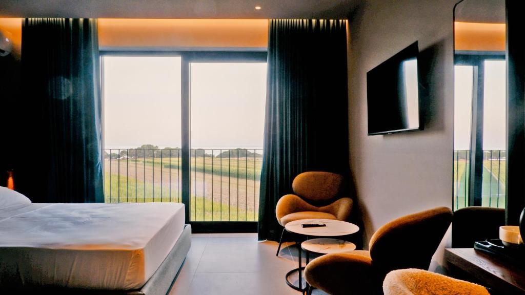 Una habitación de hotel con una cama grande, una silla, una mesita y un televisor en la pared.
